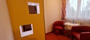 a room with a yellow door with a chair and a table at Hotel Prox in Arnstadt