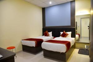 two beds in a hotel room with a large screen at HOTEL TRIDEV GRAND in Varanasi