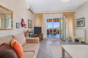 a living room with a couch and a tv at Villa Laguna in Vourvourou