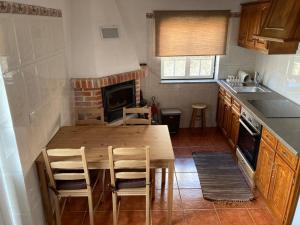 eine Küche mit einem Holztisch und Stühlen sowie einem Kamin in der Unterkunft Casa da Serra - Serra da Estrela in Seia
