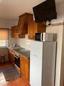 a kitchen with a white refrigerator and wooden cabinets at Casa da Serra - Serra da Estrela in Seia