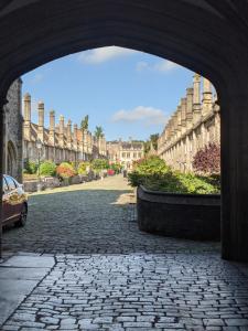 an archway leading to a cobblestone street with buildings at Namastay-Central Glastonbury in Glastonbury
