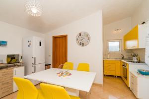 a kitchen with a white table and yellow chairs at Apartment Angie - terrace with sea view in Nečujam