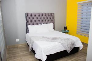 een slaapkamer met een groot bed met een grijs hoofdeinde bij Rukza's Guest House in Soweto