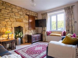 a living room with a stone wall at Lark Rise Cottage in Blockley