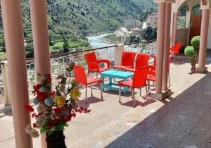 grupa czerwonych krzeseł i niebieski stół na balkonie w obiekcie Welcome Guest House w mieście Barāniā