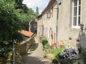 an alley in an old stone building with flowers at Village de Gîtes du Moulin Neuf in Gétigné