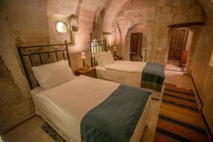 a bedroom with two beds in a stone room at Lavender Cave Hotel in Nevşehir