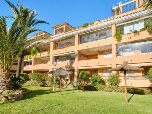 Un edificio de apartamentos con sombrillas en el patio. en SIESTA BEACH 1, CON PLAYA y PARKING, en La Cala de Mijas