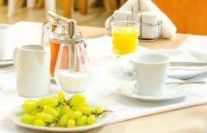 einen Tisch mit einem Teller Trauben und Tassen Milch in der Unterkunft Delfini Hotel in Skala Potamias