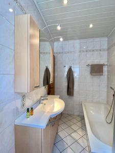 y baño blanco con lavabo, bañera y lavamanos. en Winzerhaus im Oberdorf - FeWo u Zimmer - auch kombinierbar en Erden