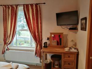 a bedroom with a tv and a desk and a window at Lion Hotel in Llanbister