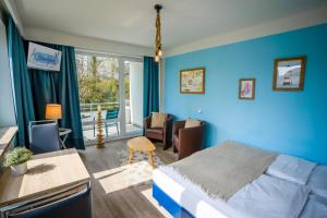 Schlafzimmer mit blauen Wänden, einem Bett und einem Schreibtisch in der Unterkunft Studio 31 "Strandgut" in Grömitz