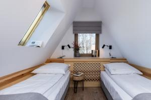 two beds in a room with a window at Villa 7 Folk & Modern in Zakopane