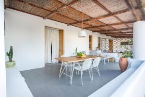 une salle à manger avec une table en bois et des chaises blanches dans l'établissement Salina Case Vacanza, à Malfa