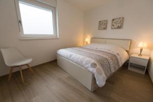 1 dormitorio con 1 cama, 1 silla y 1 ventana en Sollaris Appartement 1ère étage à 11km de Europa-Park, en Friesenheim