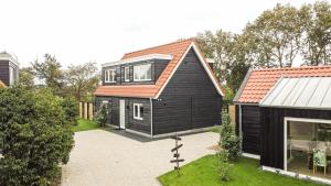 uma casa preta com um telhado laranja em Het Mienterbos em De Koog