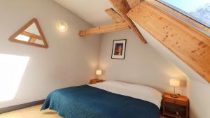 ein Schlafzimmer mit einem blauen und weißen Bett im Dachgeschoss in der Unterkunft The Old School House, Les Ougiers in Vénosc