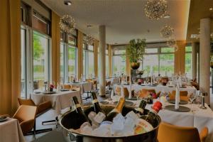 a restaurant with white tables and bottles of wine at The Bridgge Grand Boutique Hotel in Brüggen