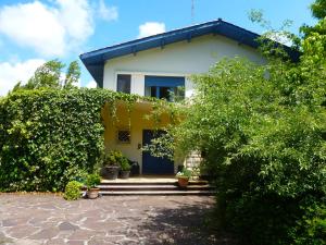 a yellow house with a blue door and some bushes at Les Eaux qui Rient in Sanguinet