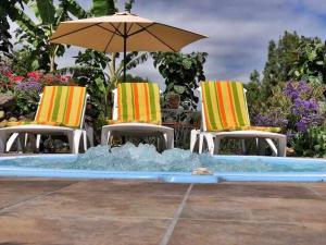 two chairs and an umbrella next to a swimming pool at FINCA LOS TAMARILLOS in Santa Cruz de Tenerife