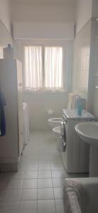 a white bathroom with three sinks and a refrigerator at Attico in centro con vista mare e monti! in Marina +13 photos