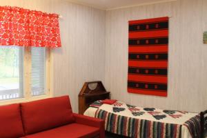 um quarto com uma cama e um sofá vermelho em Ämmän Hotelli em Suomussalmi