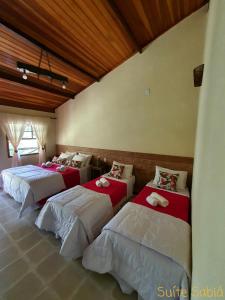Un grupo de 4 camas en una habitación en Pousada Recanto da Lunane, en Barra do Piraí