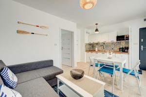 een woonkamer met een bank en een tafel bij Apartamenty Na Fali - Morski , Błękity , Marynarski in Pobierowo