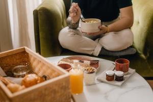 Eine Frau, die auf einer Couch sitzt und Essen isst und Orangensaft trinkt. in der Unterkunft Maison Fernand B&B in Bordeaux