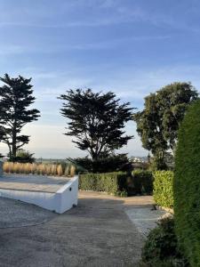 a white bench in a park with trees in the background at The Bolt Hole Hythe panoramic coast and sea views in Kent