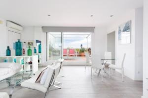 una sala de estar blanca con mesa de cristal y sillas en Stay U-nique Apartments Taulat, en Barcelona