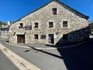 a stone building with windows and doors on a street at Auberge des Calades in Les Estables