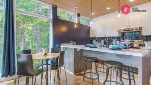 a kitchen with a bar with chairs and a table at The Marco-Polo of Portneuf - Open on nature - Private SPA Pool Sauna in Pont-Rouge