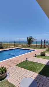 a swimming pool with the beach in the background at Amável Village de 2 suites, pé na areia em Itacimirim, Praia do Forte, Bahia in Camaçari