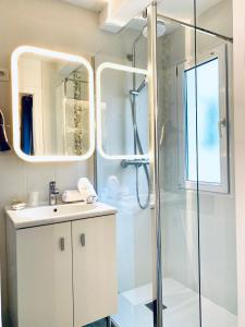 a bathroom with a shower and a sink and a mirror at Hôtel Gaspard in Le Touquet-Paris-Plage