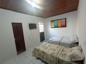 1 dormitorio con 2 camas y TV. en Suíte agradável no centro da cidade. en Boa Vista