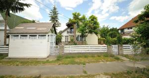 ein Haus mit einem weißen Zaun und einer Garage in der Unterkunft Levendula ház - Rosie Home in Balatonlelle