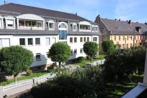 uma fila de edifícios brancos com árvores à frente em Ferienwohnung Lahann em Saalfeld