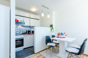 una cocina con armarios blancos y una mesa y sillas blancas. en Apartment Vedrana, en Dubrovnik