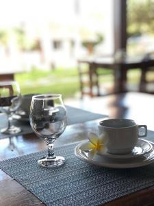 a table with a wine glass and a cup and a flower at Pousada das Palmeiras in Posse
