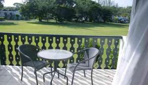 - une table et des chaises sur une terrasse avec un parcours de golf dans l'établissement 126 Friendship, Rockley Golf Club, à Bridgetown