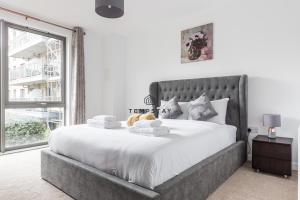 a bedroom with a large bed with a large window at Modern Private Apartment -Balcony-Tube Station in London