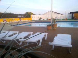 a pool with white lounge chairs and a swimming pool at 43C Medmerry Park 2 Bedroom Chalet in Earnley