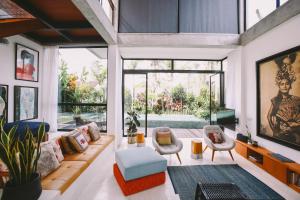 a living room with a couch and chairs and a large window at Villa Pakuk in Canggu