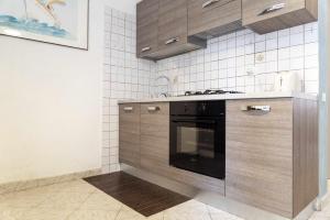 una cocina con armarios de madera y horno negro en Santa Marinella - La Terrazza sul Mare en Santa Marinella