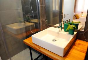 La salle de bains est pourvue d'un lavabo blanc et d'une douche. dans l'établissement Le Jardin Secret de Faro Guesthouse, à Faro