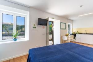 a bedroom with a blue bed and a kitchen at Casa Amarela Apartments - by Casas na Ilha in Câmara de Lobos