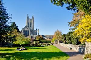 people sitting in the grass in front of a church at Luxurious Victorian villa with parking sleeps six in Bury Saint Edmunds