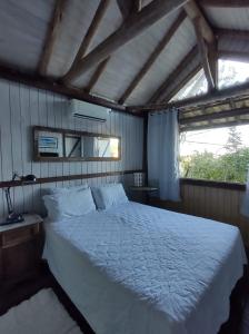 a bedroom with a large white bed with a window at Casa da Ro in Praia do Rosa